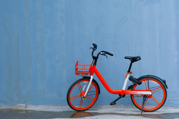 Fototapeta na wymiar The orange bicycle parking against blue wall.