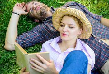 Man and girl lay on grass reading book. Couple soulmates at romantic date. Couple in love spend...