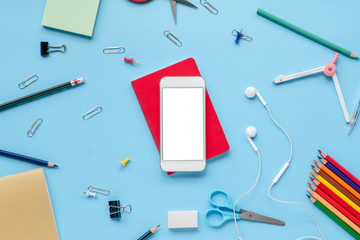 blank screen mobile phone with school supplies stationery equipment on blue backboard Flat lay with copy space. back to school concept