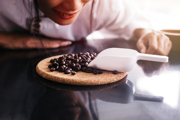 Young barista smelling coffee beans laying on table with smile with copy space