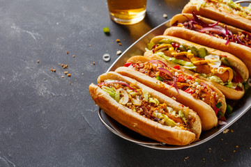 Hot dogs fully loaded with assorted toppings on a tray.