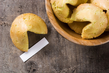 Fortune cookies in wooden bowl on wooden table. Top view