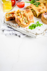 Vegetable savory strudel, homemade autumn baking, with tomatoes, bell pepper, mushrooms, wooden background copy space