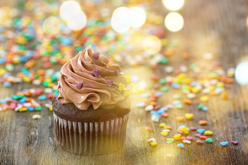 Delicious chocolate cupcake and sprinkles on table