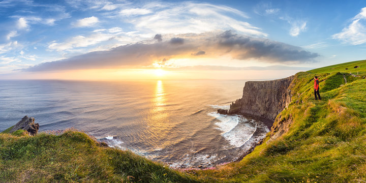 Man looking at Sunset at the Cliffs of Moher, County Clare, Munster province, Republic of Ireland, Europe.