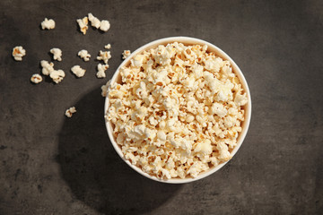 Paper bucket of tasty popcorn on grey background, top view