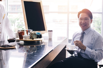 Asian smart businessman as male customer drinking coffee at cafe restaurant