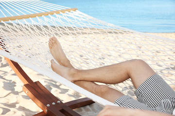 Young man resting in hammock at seaside. Summer vacation