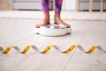 Measuring tape and blurred woman on scales