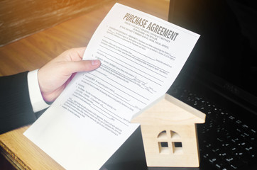 Contract for the purchase of a house. The real estate agent holds the keys. house model and...