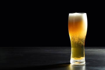 Glass with cold tasty beer on dark background