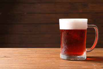 Glass mug with cold red beer on wooden table