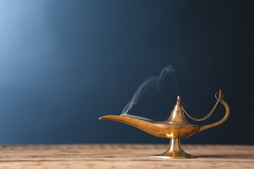 Obraz na płótnie Canvas Aladdin lamp of wishes on wooden table against color background