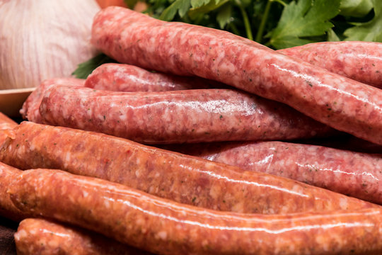 raw sausages with chilli and herbs on a wooden board with spices