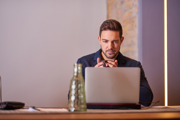 A serious handsome young businessman drinking coffee in office environment.