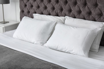 Soft white pillows on comfortable bed indoors