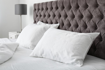 Soft white pillows on comfortable bed indoors