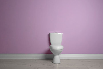 New ceramic toilet bowl near color wall with space for text