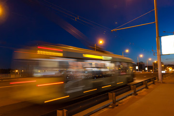 Naklejka na ściany i meble The motion of a blurred trolleybus in the street in the evening.