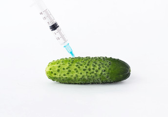 Cucumber on a white background in which the syringe gmo and nitrates are pricked, close-up,...