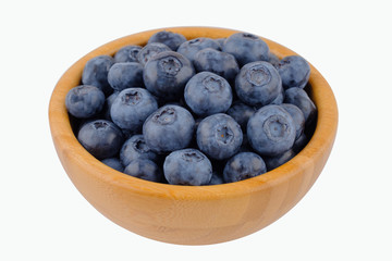 Ripe blueberries in wooden bowl isolated on white background. Side view.
