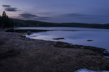 Dark and quiet water surface of the dam in the mountains. Evening nature in spring.