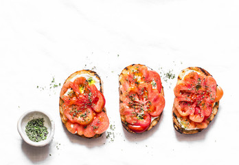 Heirloom tomatoes, feta cheese, oregano bruschetta on a light background, top view. Delicious appetizers, tapas, snack - obrazy, fototapety, plakaty