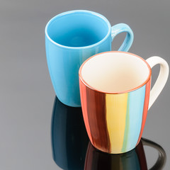 Two coffee tea porcelain clay mugs on the grey mirror background