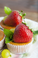 Fresh strawberry fruits over homemade muffins on white  plate decorated with mint leaves. Homemade dessert isolated. 