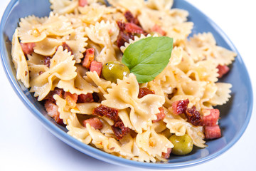 Farfalle pasta with sun dried tomato, ham and olives decorated with fresh mint