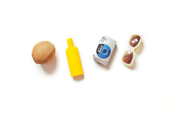 Summer holiday items/ Coconut, yellow sunscreen bottle, camera and sunglasses on a white background. Flat lay stuff, beach essentials