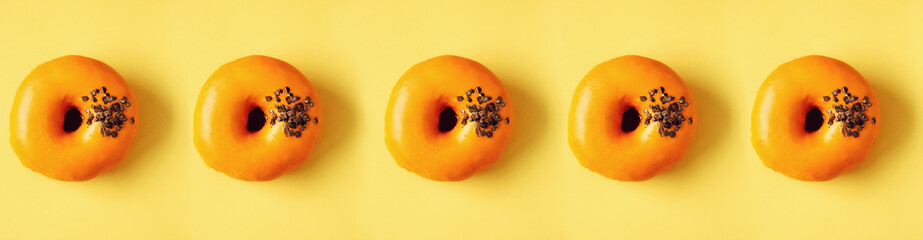 Flat lay donuts pattern on pastel orange background. Top view. Square crop. Sweet doughnut texture, copy space