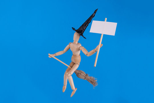 Halloween witch flying riding on witches broom holding a blank sign on solid blue background