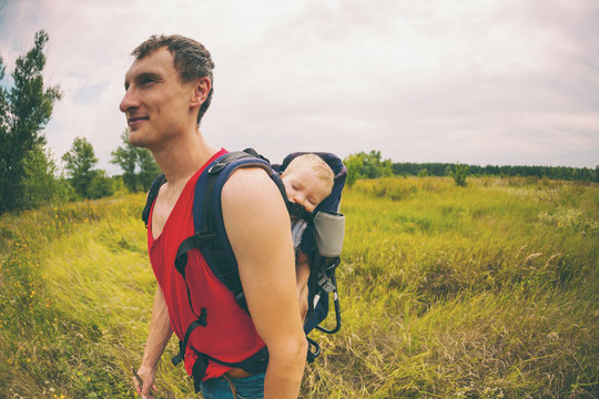 A man carries a child in a backpack.