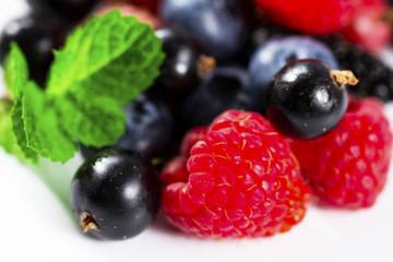 Close-up arrangement mixed, assorted berries including blackberries, strawberry, blueberry, raspberries and fresh leaf on white