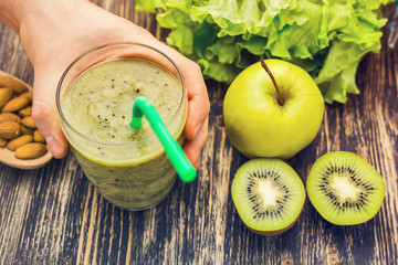 Healthy green smoothie with kiwi, apple on rustic wood background.