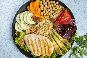 Bowl of Buddha, The concept of a healthy diet: grilled chicken, avocado, chickpeas, kinua, carrots, tomatoes, nuts. Balanced food. Top view. Copy space.