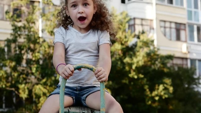 Happy young little girl spinning in a swing and smiling