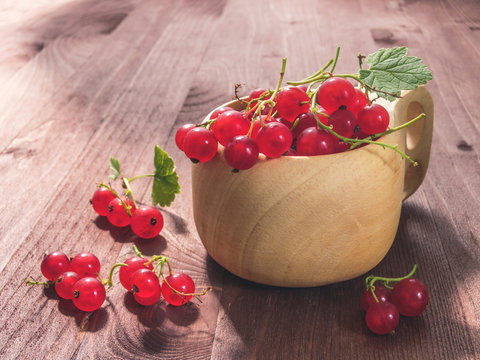 Fresh red currant in wooden mug on wood background