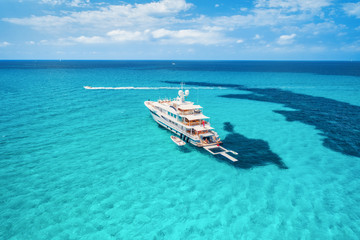 Yacht on the azure seashore in balearic islands. Aerial view of floating boat with people in transparent sea at sunny day in summer. Top view from drone. Seascape with luxury yachts in motion in bay - obrazy, fototapety, plakaty