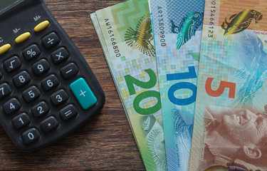New Zealand dollars and a calculator on the wooden table