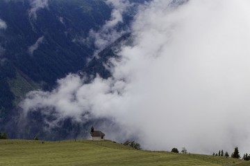Cloudy alpine landscape with a small chapel