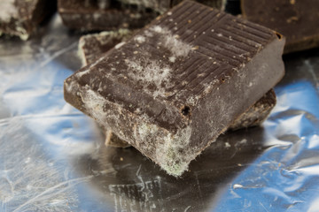 Moldy chocolate in the original packaging. Out-dated food products used for desserts.