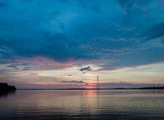 Calm evening sunset over Daugava River. High voltage tower against sunset sky. Latvia. Landscape.
