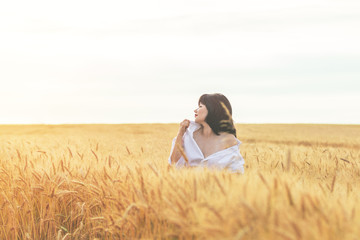 Cute happy beautiful sexy female against a background of wheat field at the time of the sunset.