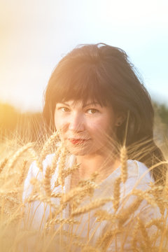 Cute happy beautiful sexy female against a background of wheat field at the time of the sunset.