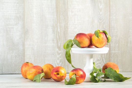 Many juicy beautiful amazing nice peaches on light wooden background. Beautiful food art background.