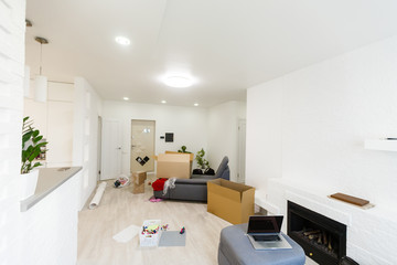 Conceptual shot of home interior during move-in with sofa in the middle and boxes lying around
