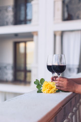 Two glasses of red wine on the balcony, hands holding them
