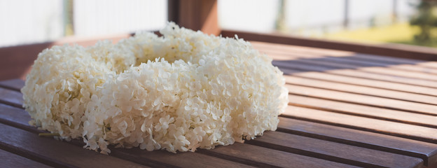 A wreath of white hydrangea on the wooden background